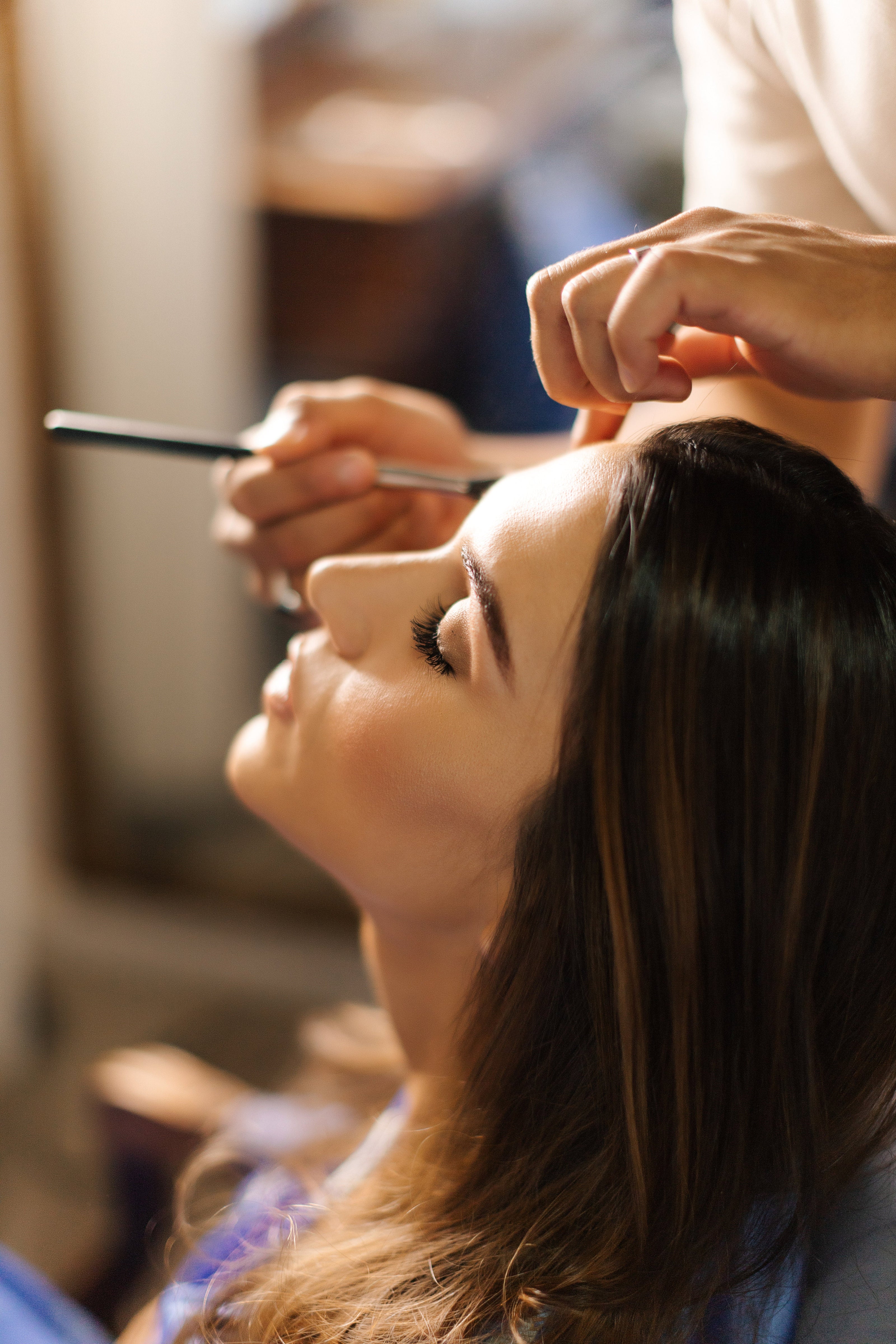 Professional makeup artist applying eyeshadow to a woman