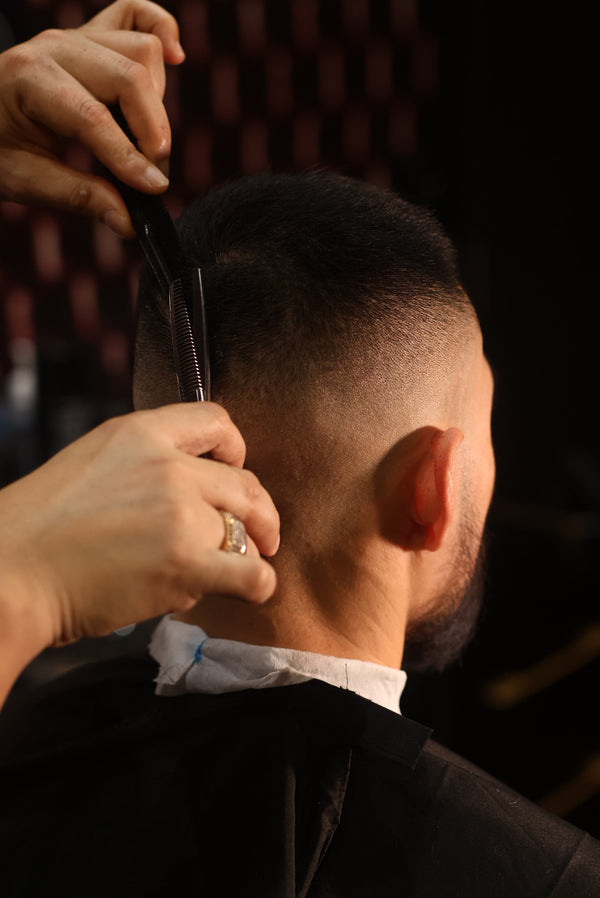 Barber giving a man a precise haircut at professional salon