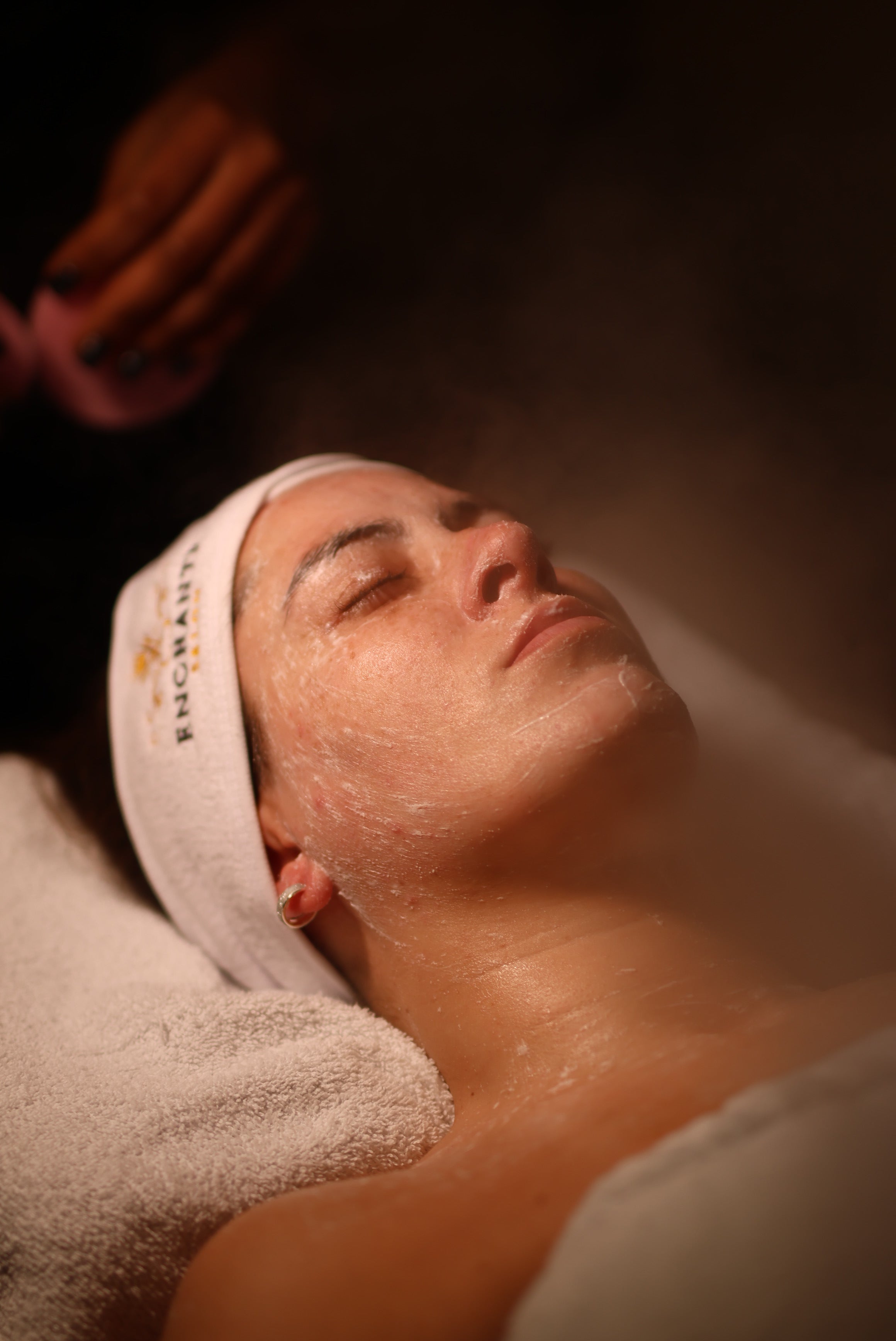 Relaxed woman receiving a professional spa facial treatment with steam therapy